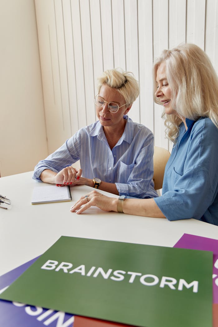 Women Sitting Beside Each Other while Brainstorming